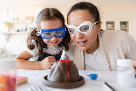 a woman and child in
goggles watch a baking soda volcano erupt